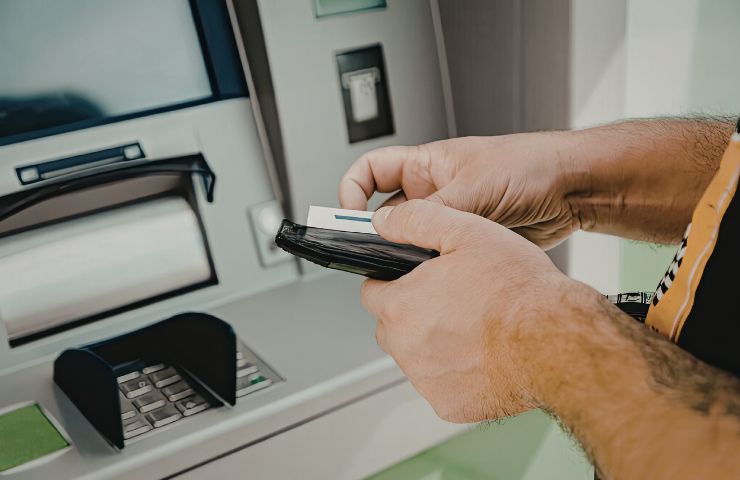 uomo con carte di credito davanti al bancomat