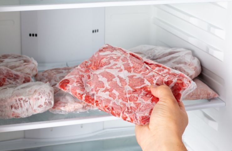 mano con prende sacchetto di carne dal freezer 