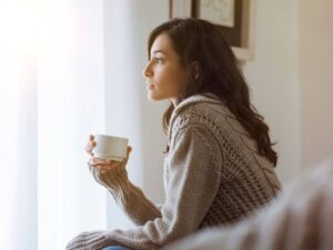 donna con tazza in mano pensierosa